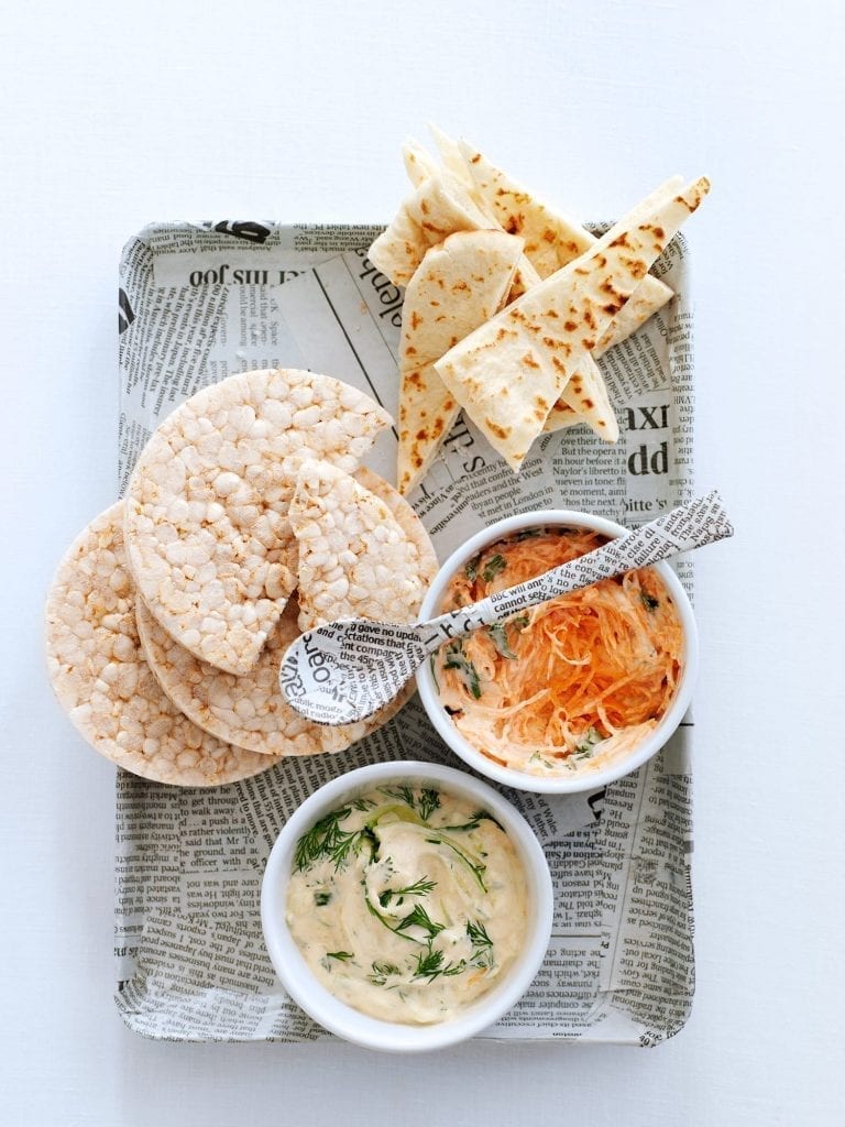 A tray of carrot and creamy dip served with pitta and rice cakes.